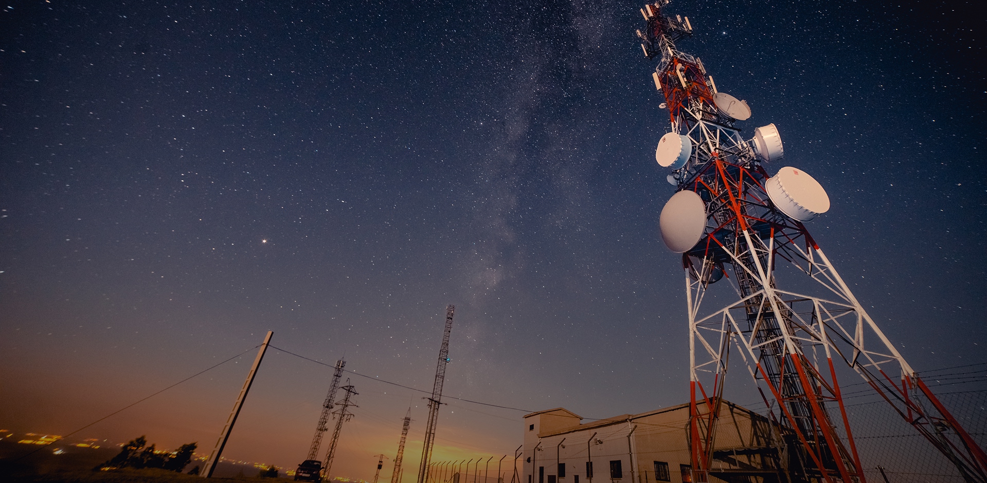Telecommunication tower and communication infrastructure operating under night sky.